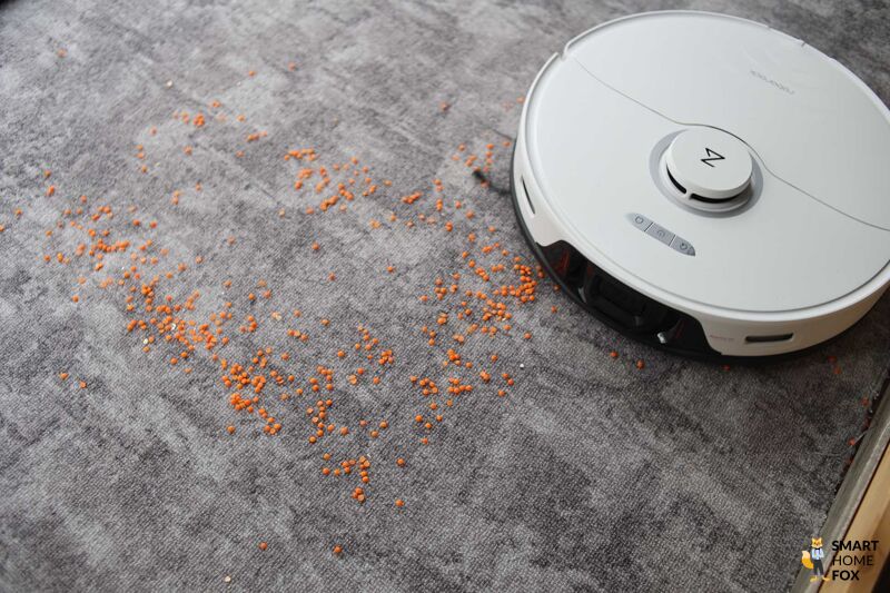 Roborock S8 Pro Ultra reinigt beim Saugtest Linsen auf einem Teppichboden.